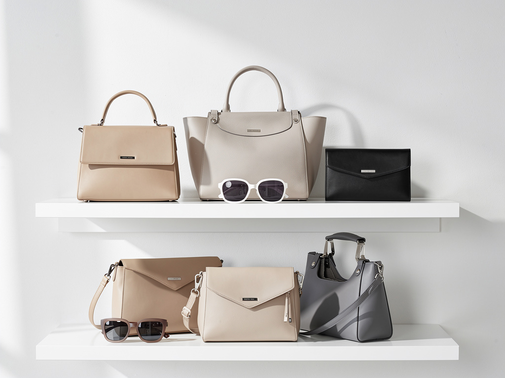 A small, carefully arranged selection of bags and sunglasses on clean shelves with plenty of white space.
